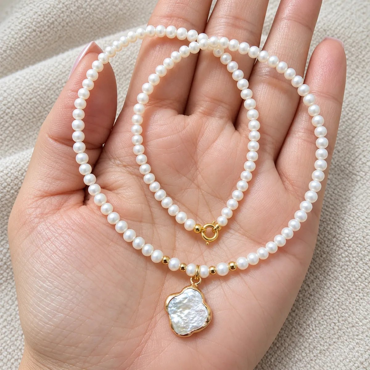 Colier cu perle naturale și charm trifoi, ținut în palmă